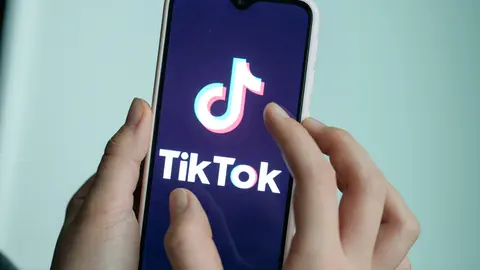 FILED - 13 November 2019, Berlin: A girl holds her smartphone with the logo of the short video app TikTok. Social media platform TikTok has lodged a legal objection through the German courts to a requirement that it pass on large quantities of user data to the country's federal police, a spokeswoman for the administrative court in Cologne said on Thursday. Photo: Jens Kalaene/dpa-Zentralbild/dpa.