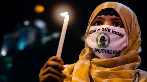11 February 2022, India, Rajpur Sonarpur: A Muslim woman holds a candle during a protest against the recent hijab ban in some of the colleges of the southern Indian state of Karnataka. Photo: Sankhadeep Banerjee/ZUMA Press Wire/dpa.