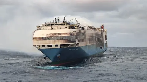 HANDOUT - 18 February 2022, Portugal, ----: Smoke rises from a freighter in the Atlantic Ocean south of the Azores. A freighter carrying about 4000 German cars belonging to the Volkswagen Group caught fire, according to the Portuguese Navy. The 22 crew members had abandoned the almost 200-metre-long Felicity Ace and were brought to safety, a spokesperson told dpa on Friday. (best quality available) Photo: ---/Marinha Portugal/dpa - ACHTUNG: Nur zur redaktionellen Verwendung im Zusammenhang mit der aktuellen Berichterstattung und nur mit vollständiger Nennung des vorstehenden Credits.