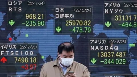 24 February 2022, Japan, Tokyo: A man walks past an electronic stock exchange board displaying Japan's Nikkei stock index in downtown Tokyo. Japan's Nikkei index fell below 26,000 points on Thursday for the first time since November 2020 after Russian troops attacked Ukraine in the morning. Photo: Rodrigo Reyes Marin/ZUMA Press Wire/dpa.