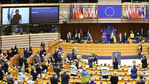 HANDOUT - 01 March 2022, Belgium, Brussels: Ukrainian President Volodymyr Zelensky (on screen) is applauded as he addresses members of the European Parliament via video conference during an extraordinary plenary session of the European Parliament on the situation in Ukraine after the Russian invasion. Photo: Alain Rolland/EU Parliament/dpa - ATTENTION: editorial use only and only if the credit mentioned above is referenced in full.