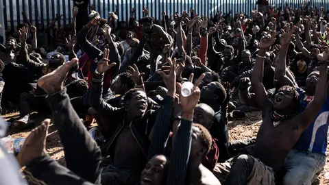 02 March 2022, Spain, Melilla: Migrants cheer after they managed to jump the border fence of Melilla. According to Guardia Civil sources, up to 2,000 people of sub-Saharan origin have attempted to cross the Melilla border fence, of which 500 have succeeded and made their way to the Temporary Immigrant Stay Center (CETI). Photo: Ilies Amar/EUROPA PRESS/dpa.