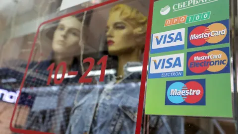 06 March 2022, Russia, Saint Petersburg: The logos of various payment systems with Sberbank written on them are pasted on a window of a store. Russia's largest bank - Sberbank - wants to ensure that people can pay and withdraw money with their cards even after Visa and Mastercard credit cards are switched off. Photo: Igor Russak/dpa.