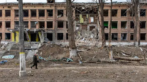 07 March 2022, Ukraine, Vasylkiv: A woman walks past a damaged secondary school building after shelling by Russian forces. Attacks and fighting continued 13 days after the Russian invasion. Photo: Mykhaylo Palinchak/SOPA Images via ZUMA Press Wire/dpa.