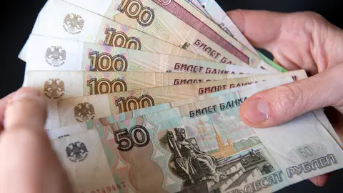 28 February 2022, Bavaria, Munich: A woman holds Russian ruble banknotes in her hands. The European Union put its severe sanctions against the Russian Central Bank into effect on Monday night. Photo: Sven Hoppe/dpa.