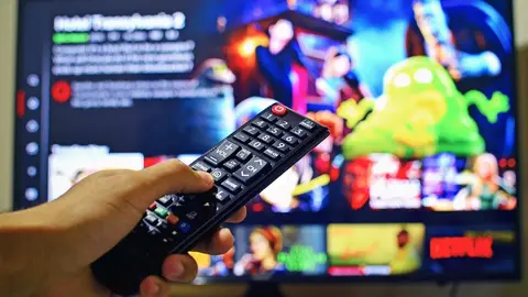 A Netflix user with the TV remote. Photo: Pixabay.
