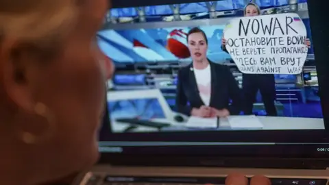 FILED - 14 March 2022, Hamburg: A person watches on a monitor a scene from the main evening news broadcast on Russian state television, as it is interrupted by an anti-war protester. Photo: Axel Heimken/dpa.