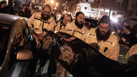 29 March 2022, Israel, Bnei Brak: Medics transport a body following a shooting attack. A man riding a motorcycle reportedly opened fire on passers-by in the city of Bnei Brak near Tel Aviv killing at least four people in the third incident of its kind within a week. Photo: Ilia Yefimovich/dpa - ATTENTION: graphic content.