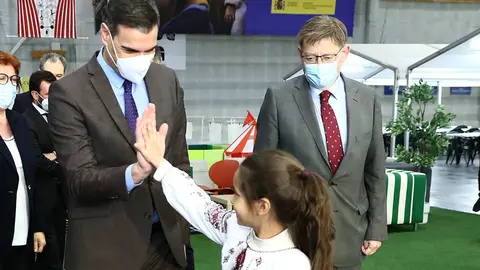 03/31/2022. Prime Minister Pedro Sanchez (L) greets a girl staying at the Reception, Care and Referral Center for Ukrainian refugees in the City of Light (Alicante), in the presence of the president of the Generalitat Valenciana, Ximo Puig. Photo: Moncloa.