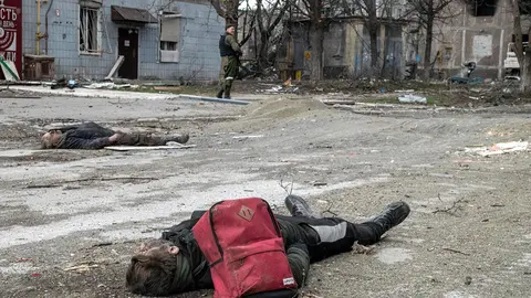 03 April 2022, Ukraine, Mariupol: The bodies of a civilians lay in an intersection in the centre of Mariupol as a Donetsk People's Republic fighter stands guard. Photo: Maximilian Clarke/SOPA Images via ZUMA Press Wire/dpa - ACHTUNG: Graphic Content.