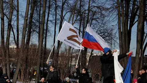 18 March 2022, Russia, Moscow: People hold flags on the sidelines of a concert held to mark the eighth anniversary of Russia's annexation of Crimea. Photo: Str/dpa.