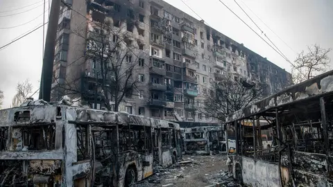 23 March 2022, Ukraine, Mariupol: Burned buses are seen in front of a destroyed residential complex in the besieged Ukrainian city of Mariupol. Photo: Maximilian Clarke/SOPA Images via ZUMA Press Wire/dpa.