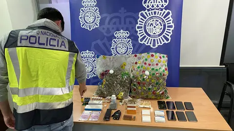 An agent of the National Police, next to the drugs and other materials seized during the house search. Photo: Policia Nacional.