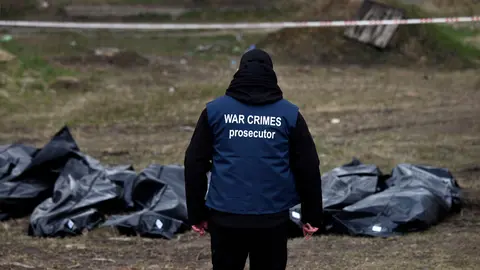 11 April 2022, Ukraine, Butscha: An investigator wears a vest labeled "War Crimes Prosecutor" and begins collecting evidence of war crimes alongside bodies from a mass grave behind St. Andrew's Church. Photo: Carol Guzy/ZUMA Press Wire/dpa.