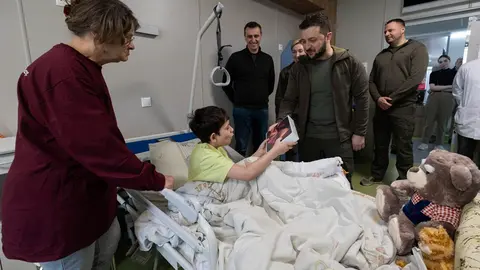 HANDOUT - 26 April 2022, Ukraine, Kiev: Ukrainian President Volodymyr Zelensky (C) gives an iPad to Ilya Matvienko, who is being treated at Okhmatdyt National Children's Specialized Hospital in Kiev. The boy is one of two orphans evacuated during the Russian attack on the city of Mariupol. Photo: Ukraine Presidency/Planet Pix via ZUMA Press Wire/dpa.