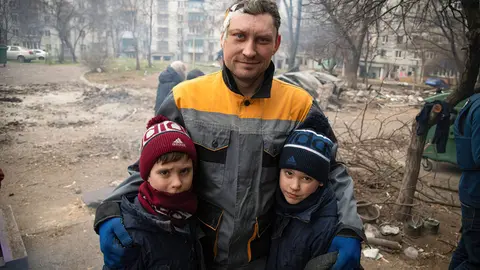 03 April 2022, Ukraine, Mariupol: A wounded man stands with his children in a destroyed neighbourhood in Mariupol during Russia's invasion of Ukraine. By capturing the Ukrainian port city of Mariupol, Russia says it wants to create a secure land link to the annexed Black Sea peninsula of Crimea. Photo: Maximilian Clarke/SOPA Images via ZUMA Press Wire/dpa.