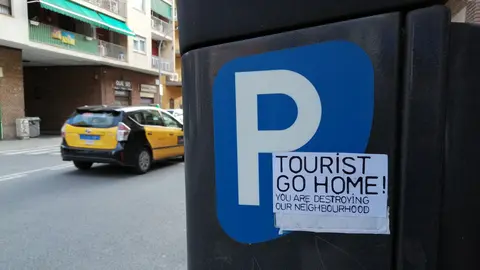 A sticker on a parking payment machine in the Barceloneta neighborhood in Barcelona shows rejection against tourists. Photo: © The Nomad Today.