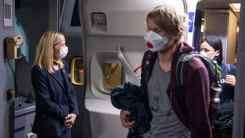 FILED - 08 April 2020, Frankfurt_Main: A flight attendant and passengers are seen wearing face masks after landing by Lufthansa's Boeing 747 at Frankfurt Airport. The EU has announced the relaxing of anti-Covid measures for air travellers, dropping the recommendation to wear masks in airports and on aircraft from Monday, the European Aviation Safety Agency (EASA) and the EU health authority ECDC said Wednesday. Photo: Boris Roessler/dpa.