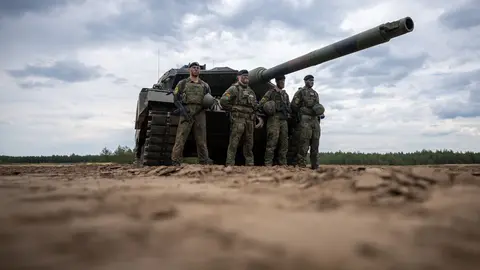 07 June 2022, Lithuania, Pabrade: Soldiers stand in front of a German Army Leopard-2 tank used by the NATO Enhanced Forward Presence Battle Group (eFP battalion) during a visit by German Chancellor Olaf Scholz to Camp Adrian Rohn. Photo: Michael Kappeler/dpa.