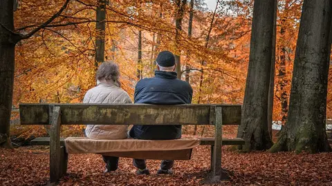 An elderly couple sitting on a bench watching the landscape. Photo: Pixabay.