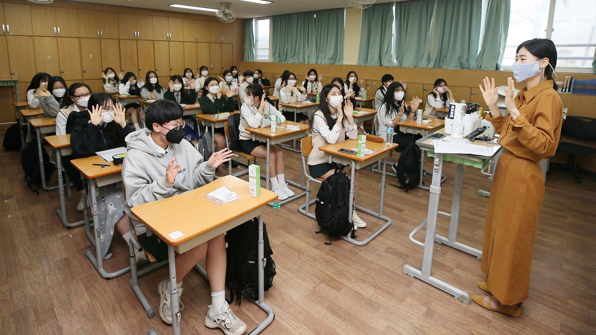 A teacher and high school students wearing protective face masks exchange greetings in a classroom as a school reopens, following the global outbreak of the coronavirus disease (COVID-19), in Cheju, South Korea, May 20, 2020. Yonhap/via REUTERS ATTENTION EDITORS - THIS IMAGE HAS BEEN SUPPLIED BY A THIRD PARTY. SOUTH KOREA OUT. NO RESALES. NO ARCHIVE.