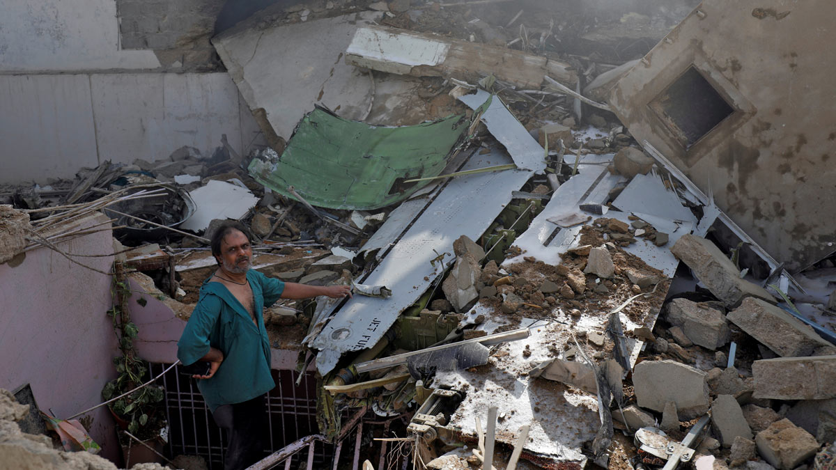 A man stands on the debris of a house at the site of a passenger plane crash in a residential area near an airport in Karachi, Pakistan May 22, 2020. REUTERS/Akhtar Soomro