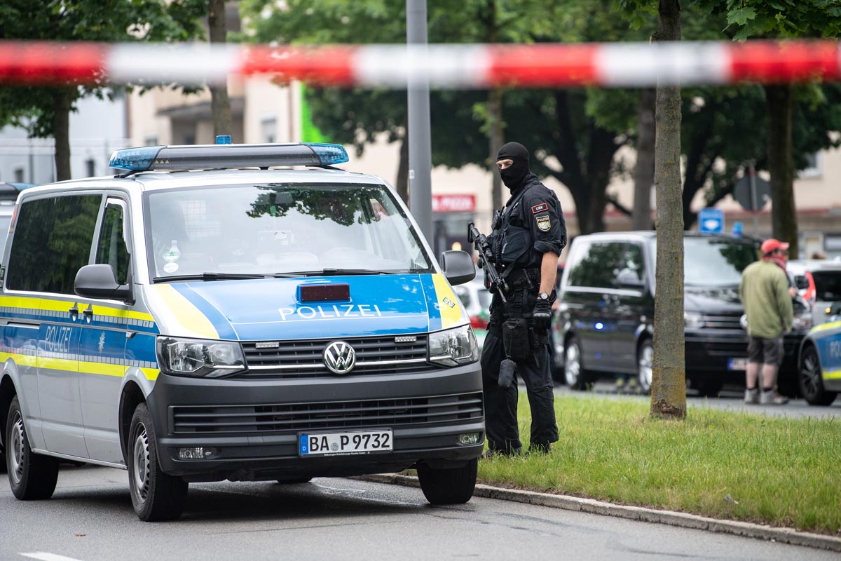 10 June 2020, Bavaria, Munich: A policeman with a machine pistol stands at the scene, where a vehicle drove into a group of people. The car passengers then attacked the group they had driven into. Three were injured, either from the impact or in the subsequent brawl. Photo: Matthias Balk/dpa