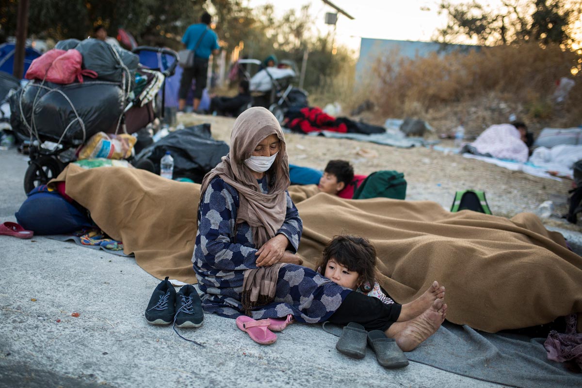 11 September 2020, Greece, Moria: A woman sits with her child at the side of a road near the burnt-out refugee camp Moria, that was almost completely destroyed in a fire the broke out on Wednesday. More than 12,000 migrants, who lost what homes they had in the blaze that might have been intentionally set, had to spend the night on the streets. Photo: Socrates Baltagiannis/dpa.