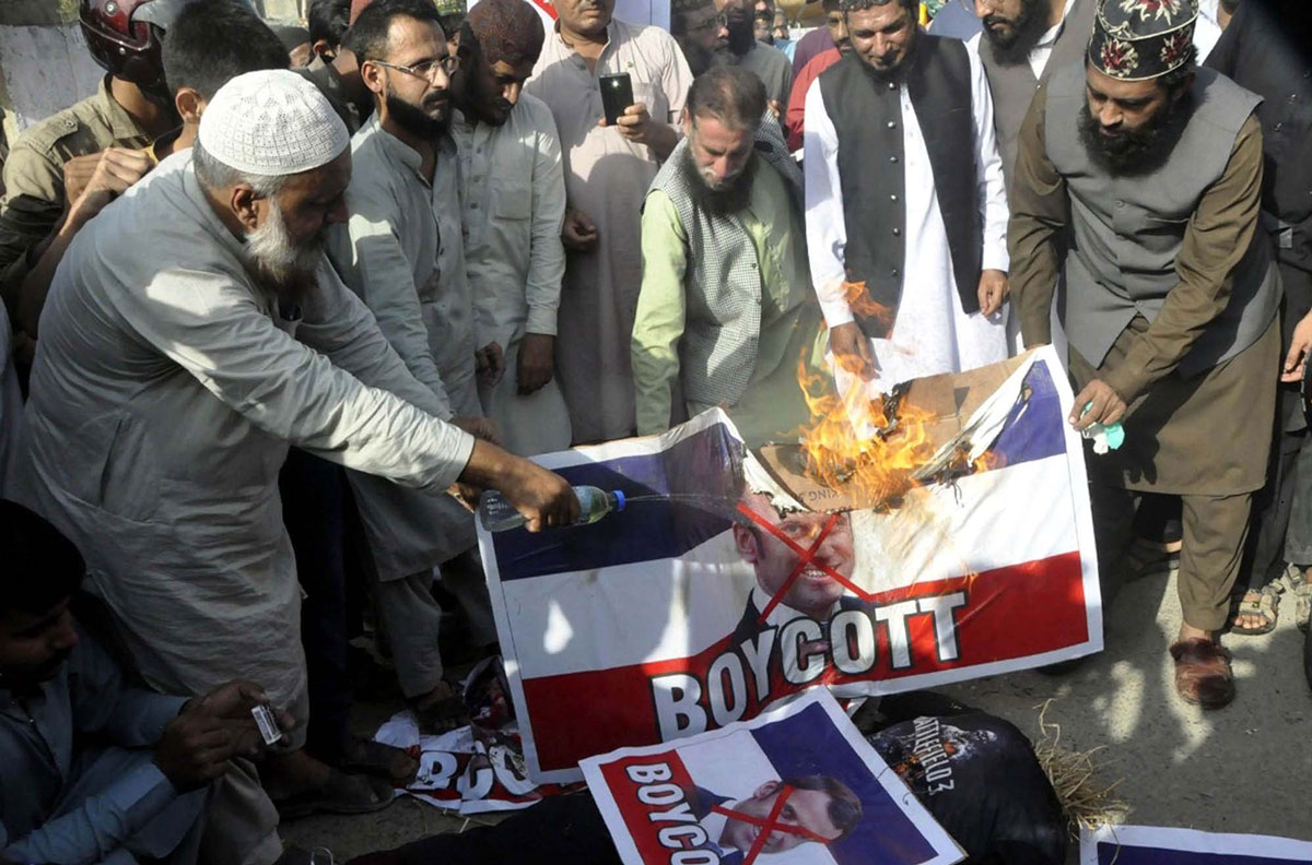 27 October 2020, Pakistan, Karachi: Pakistani demonstrators burn a banner depicting French President Emmanuel Macron on the French flag, during a protest against Macron's comments on Islam's prophet Muhammad cartoons. Photo: Ppi/dpa.