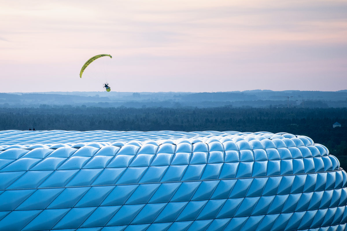 15 June 2021, Bavaria, Munich: A Greenpeace activist flies with a parachute above the Allianz Arena before the start of the UEFA EURO 2020 Group F soccer match between France and Germany. Photo: Matthias Balk/dpa