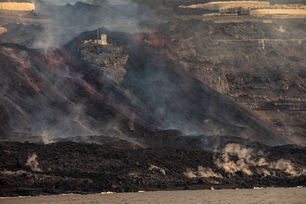 10 November 2021, Spain, La Palma: Lava flows into the sea. The amphibious ship of the Spanish Navy Castilla arrived in La Palma to carry out the transferring process of the farmers to their work areas after being isolated due to the Volcanic eruption. Photo: Kike Rincón/EUROPA PRESS/dpa
