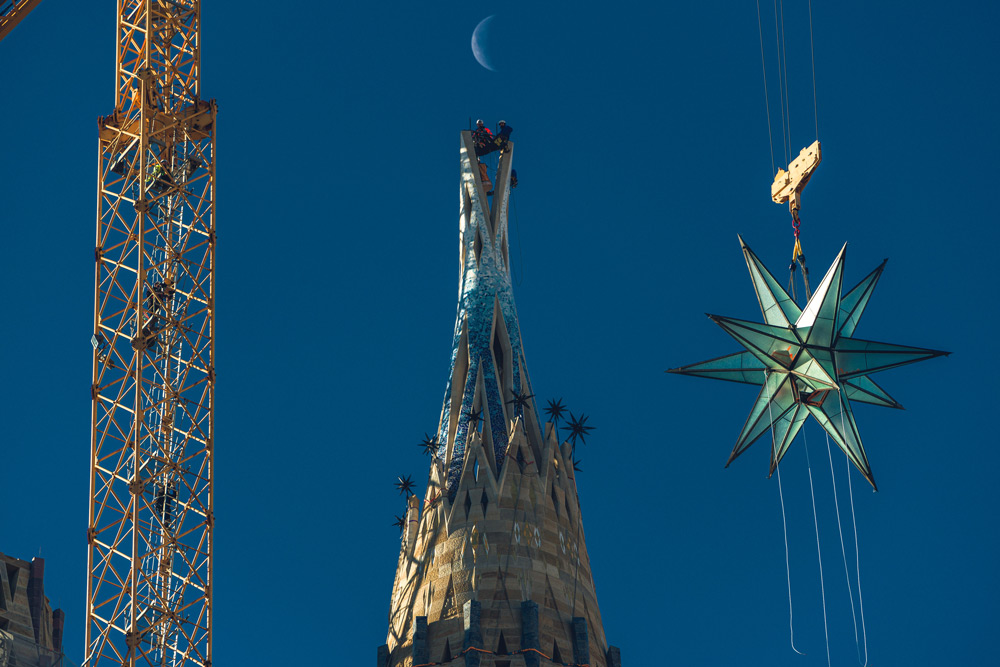 29 November 2021, Spain, Barcelona: A giant crystal star hangs on a crane making its way up to be installed on top of the Virgin Mary's Spire of the Basilica 'La Sagrada Familia'. Photo: Matthias Oesterle/ZUMA Press Wire/dpa.
