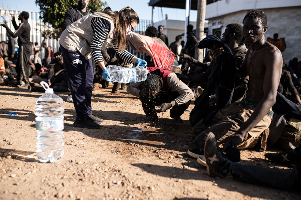 02 March 2022, Spain, Melilla: A volunteer attends ti migrants who managed to jump the border fence of Melilla. According to Guardia Civil sources, up to 2,000 people of sub-Saharan origin have attempted to cross the Melilla border fence, of which 500 have succeeded and made their way to the Temporary Immigrant Stay Center (CETI). Photo: Ilies Amar/EUROPA PRESS/dpa,